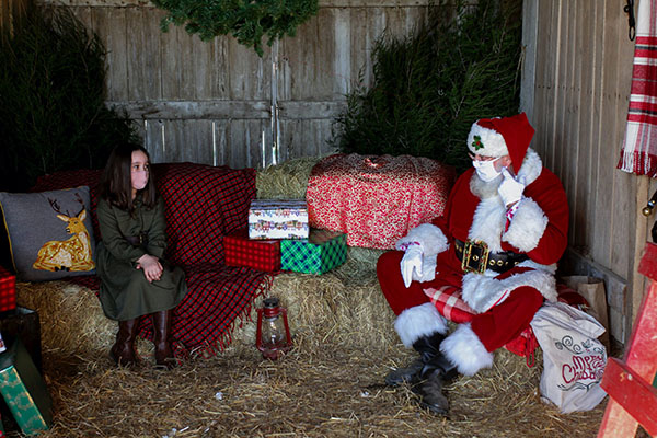 John Wenstrup as Santa Claus, sitting with a child outdoors while social distancing and wearing face masks