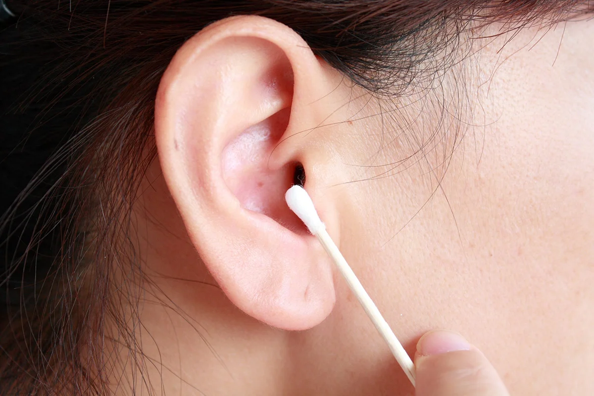 Closeup image of a person's ear and a cotton swab