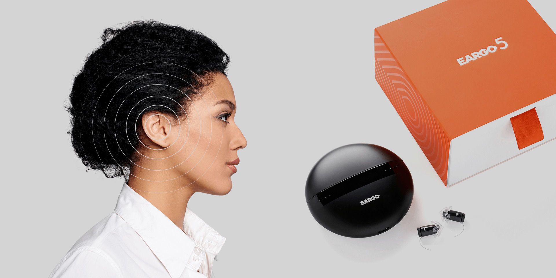 Woman with mild hearing loss next to the charger and box for Eargo 5 hearing aids