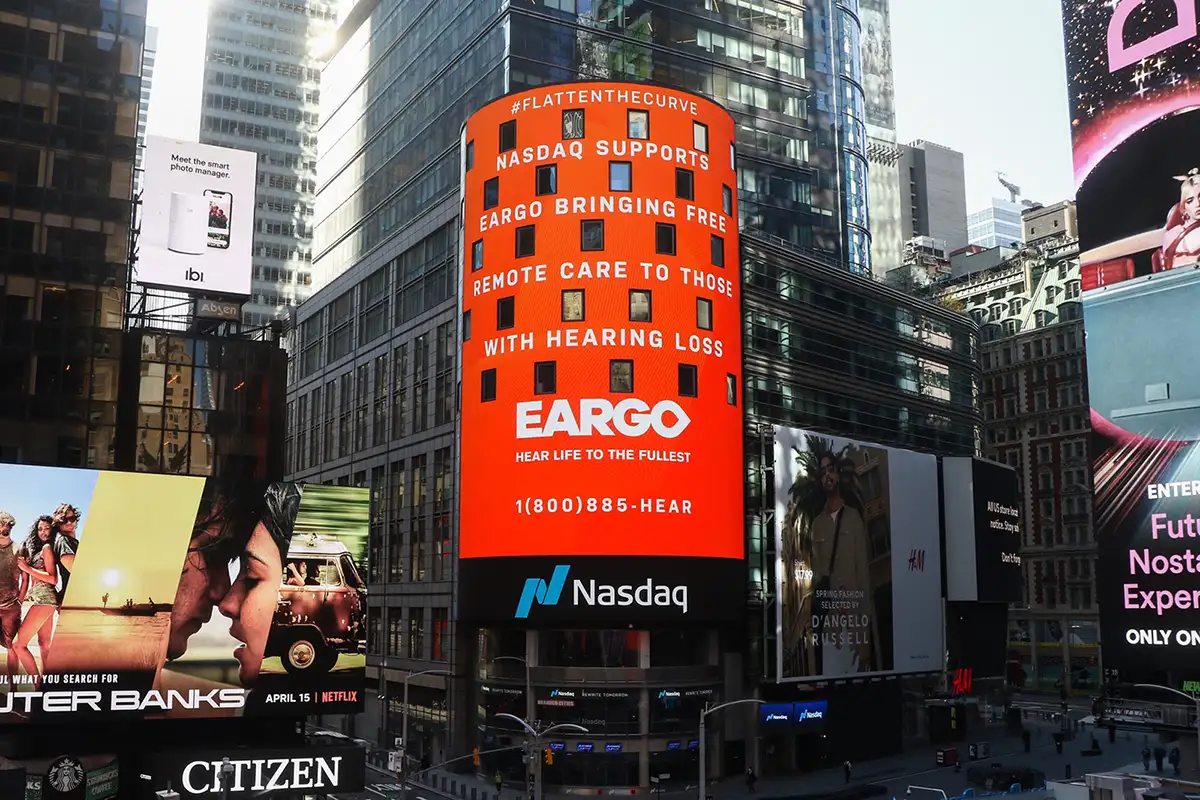 Photo of NASDAQ screen in Times Square, displaying a message supporting Eargo's efforts to provide remote care