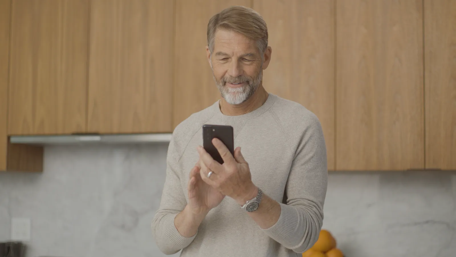 Mark using phone in kitchen